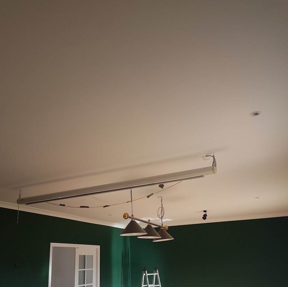 Freshly finished ceiling in a room with deep green walls and white wainscoting