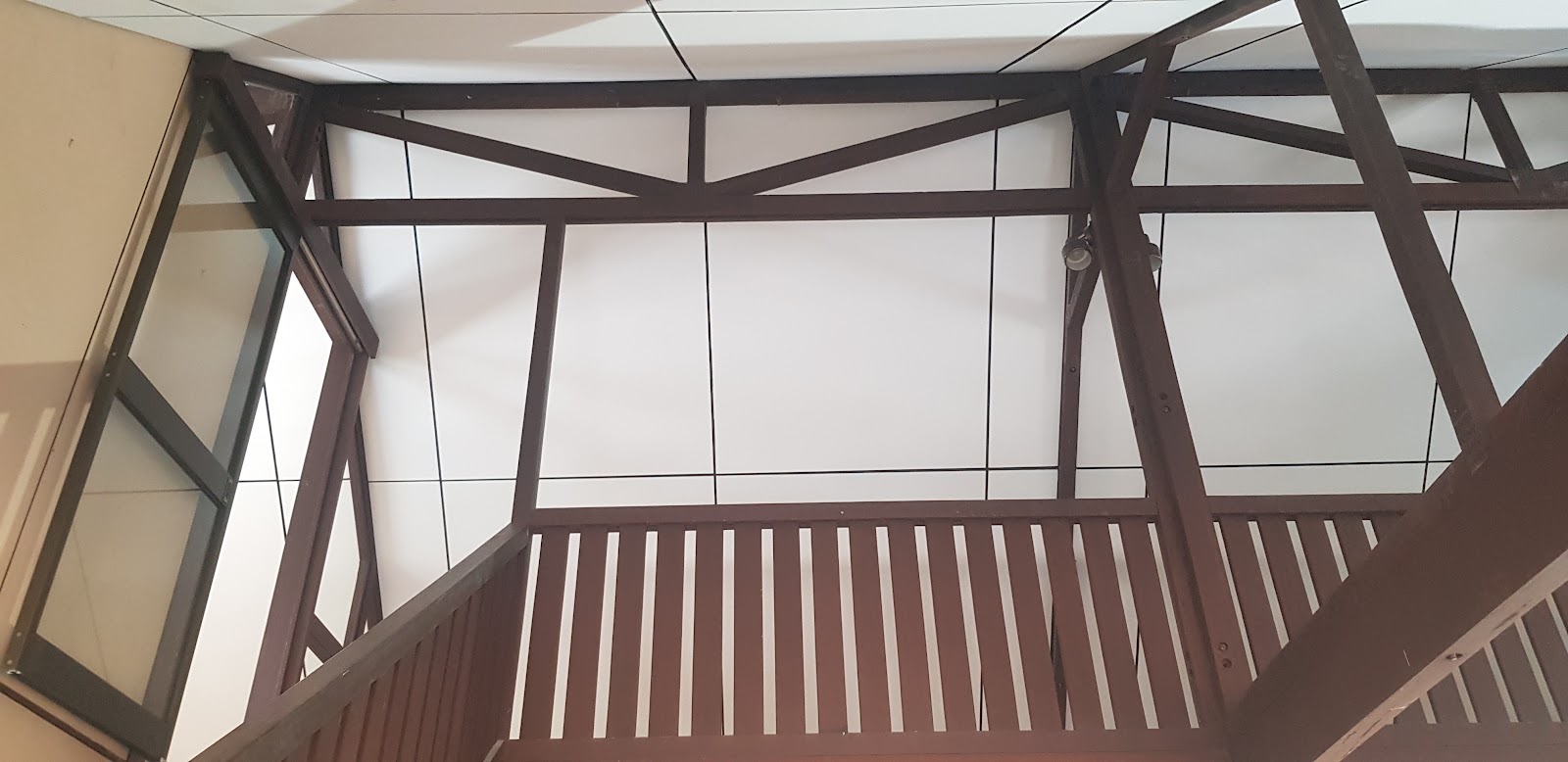 New white ceiling sheets fitted between dark timber trusses above a mezzanine
